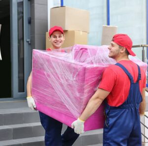 Zwei Umzugshelfer tragen ein in Folie gepacktes Möbelstück – Umzug in Calw