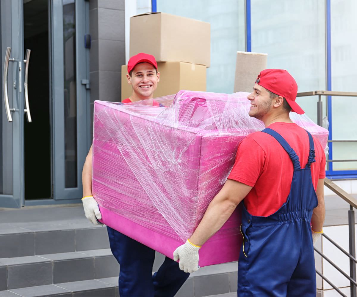 Zwei Umzugshelfer tragen ein in Folie gepacktes Möbelstück – Umzug von Calw nach Färöer